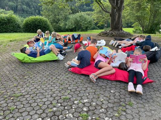 Schüler liegen auf Sitzsäcken draußen und lesen