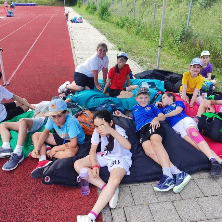 Schüler ruhen sich am Rand des Sportplatzes aus