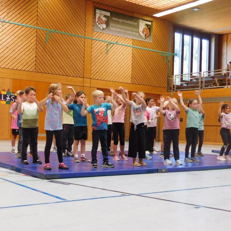 Schüler tanzen auf blauen Turnmatten