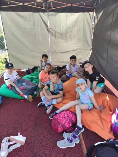 Mehrere Kinder und Jugendliche posieren zusammen unter einem großen Camping- oder Festzelt.