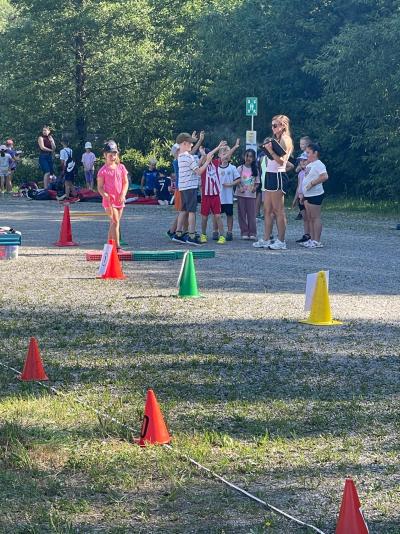 Eine Gruppe von Menschen führt ein Spiel mit bunten Kegeln auf einem grasbewachsenen Feld in einem Park durch.