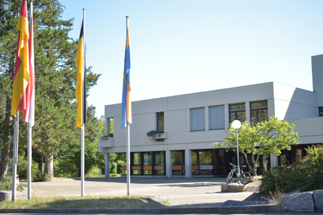 Schulgebäude der Grundschule mit drei Fahnen im Vordergrung